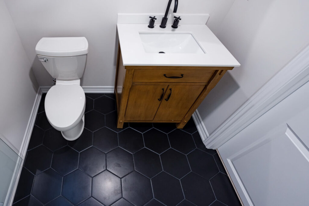 wooden single vanity with white ceramic countertop with round mirror and toilet seat