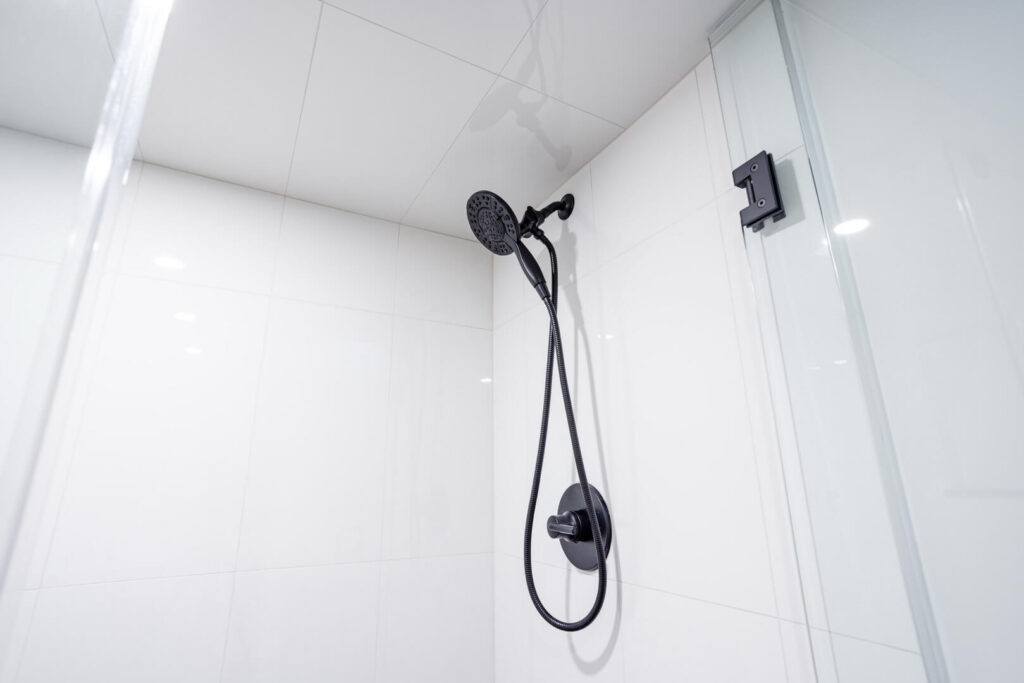 glossy white tiled shower wall with wall mounted shower heads