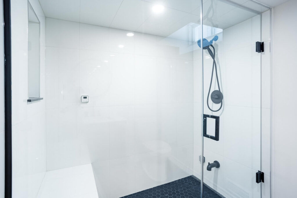 corner shower unit with installed shower head and sitting bench