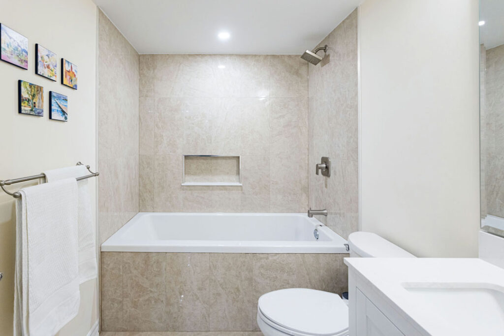 marble tiled wall with floor mounted bathtub and wall mounted shower heads