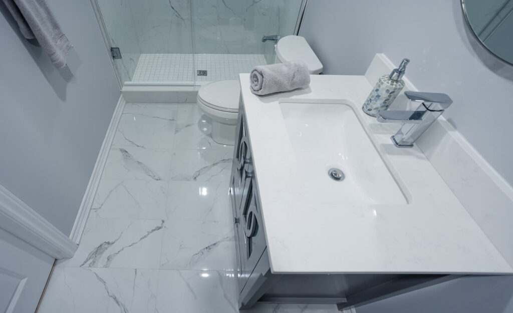 basement bathroom marble tile flooring with glass cabinet door vanity and counetertop