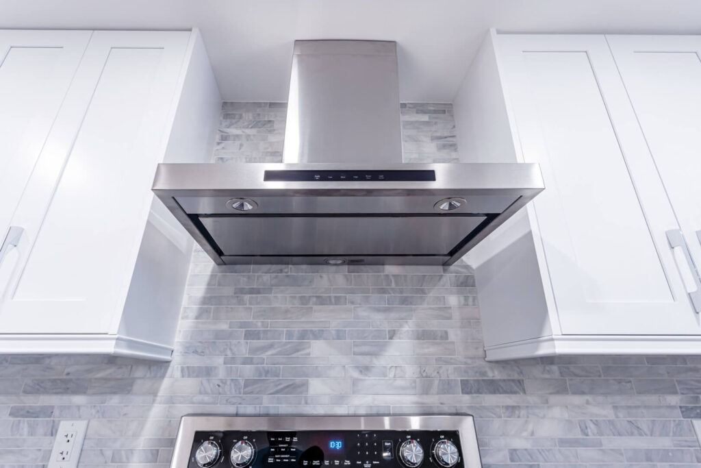 kitchen tiled wall with installed electric chimney and cooktop