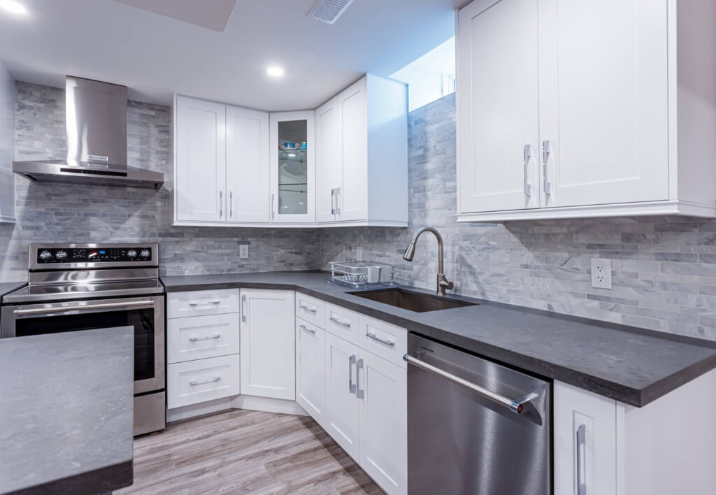 white cabinets with grey countertop and textured tiled wall
