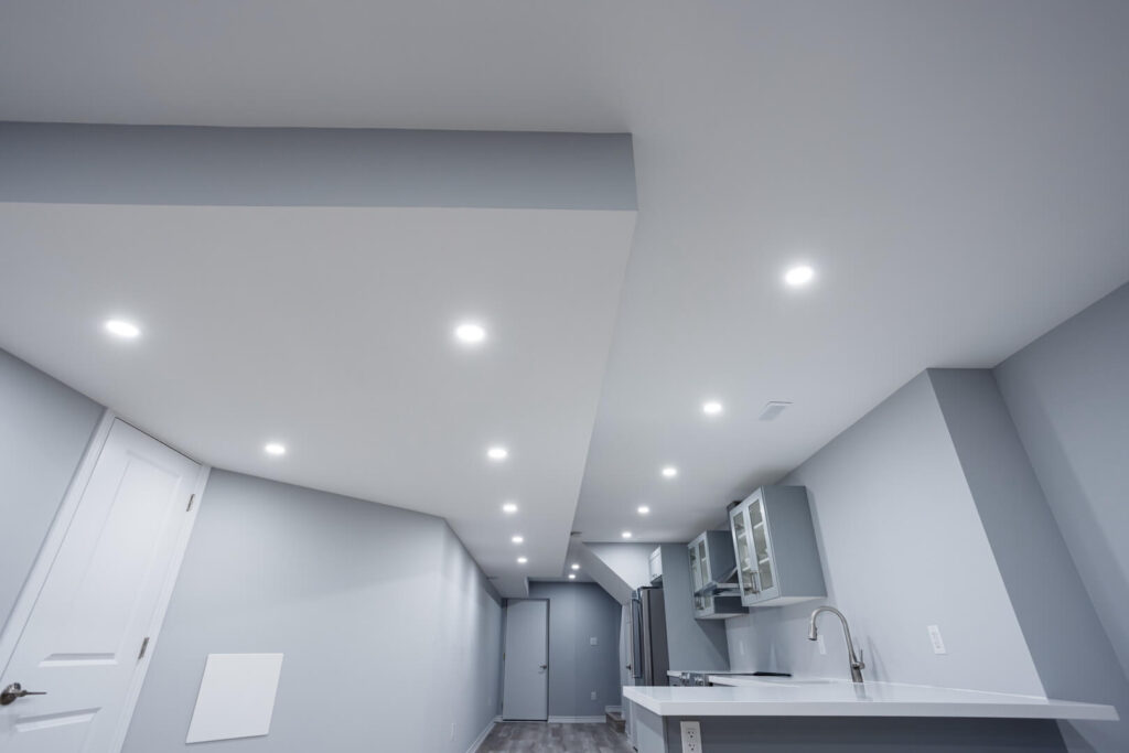 basement kitchen renovation with grey theme cabinets, kitchen wall and white countertop