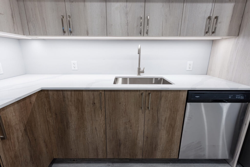 basement kitchen wooden cabinets with hardware handles for access and single sink with faucets