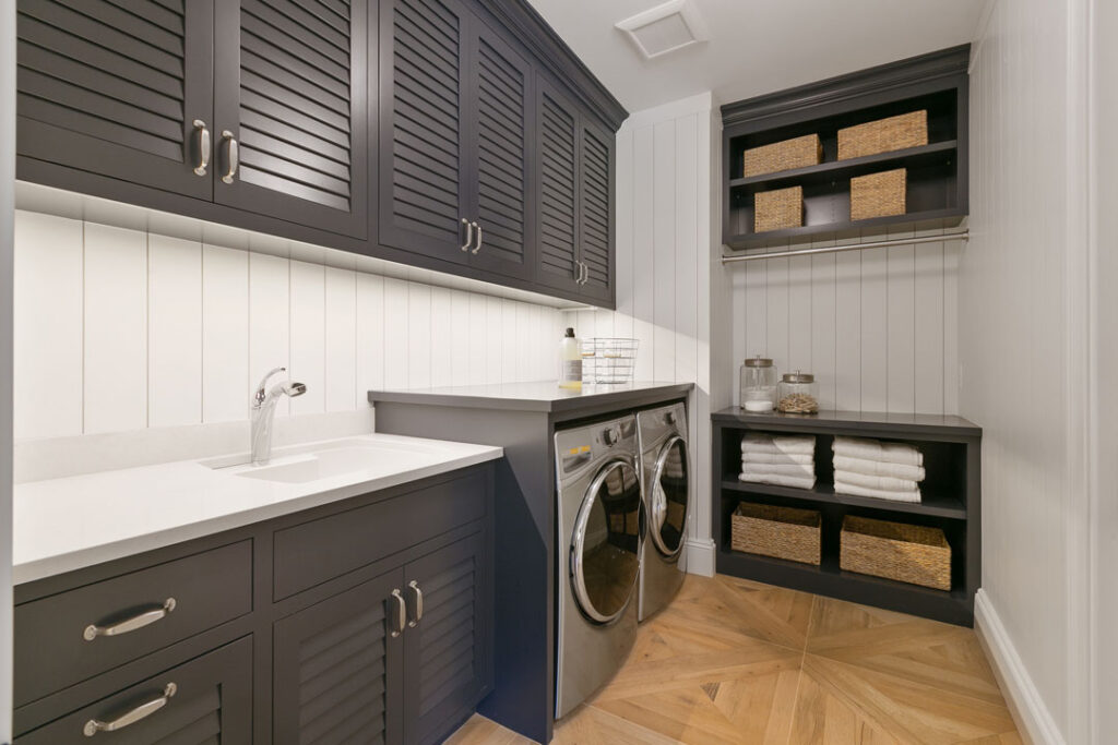 High-end laundry room renovation with built-in storage and elegant finishes stylish laundry room renovation with dark shaker cabinets, wood floors, and storage baskets