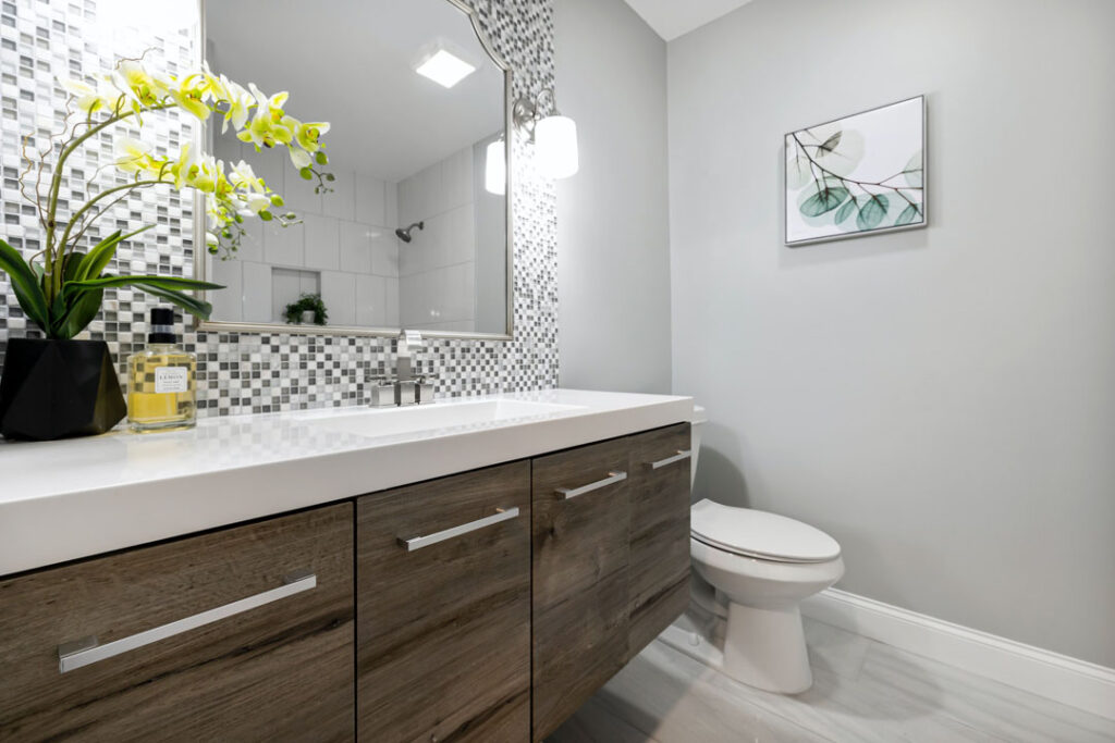 High-end powder room remodeling in Toronto with wood vanity and tile design Stylish powder room remodeling with mosaic backsplash and modern finishes