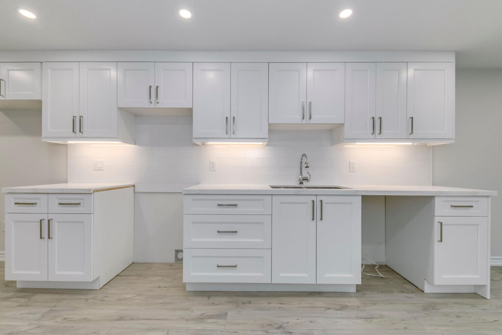 all white kitchen with white cabinets, countertop, island and vinyl flooring