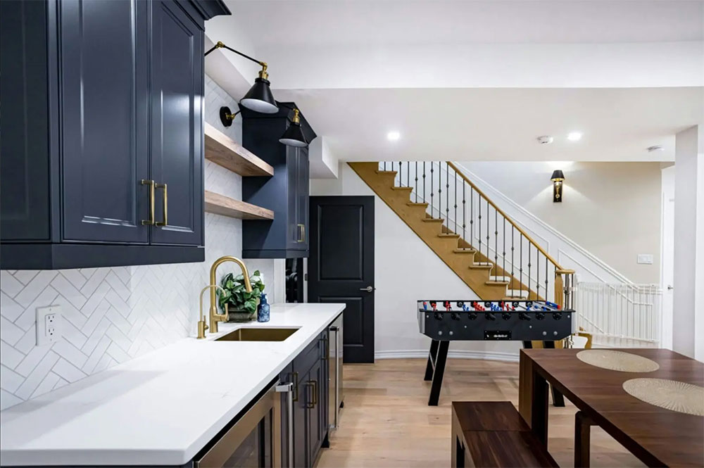 Professional vs. DIY Renovations: Basement kitchen with stairwell, dark cabinets and fooseball table