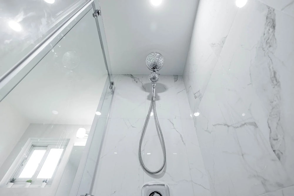 Modern walk-in shower with marble tile walls and ceiling-mounted showerhead